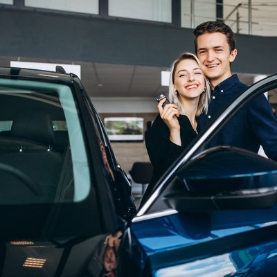 Young couple choosing a car in a car show room